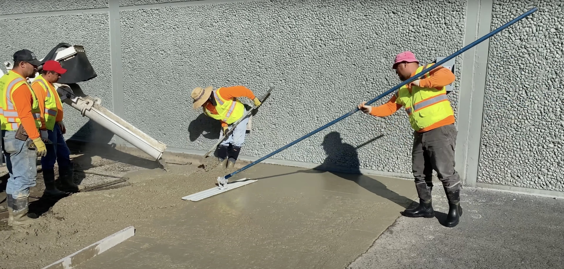 Professional concrete installation team with safety equipment and proper techniques Professional concrete crew working on large commercial concrete project with proper safety equipment