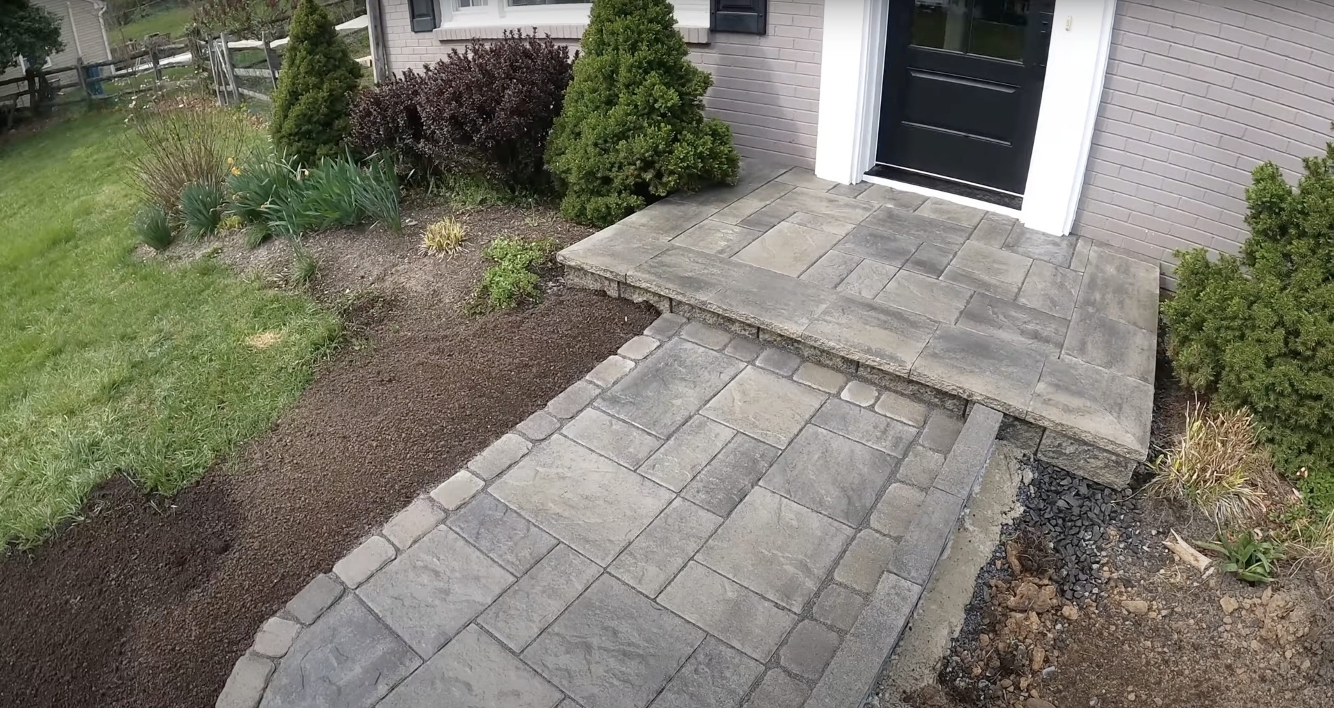 Stamped decorative concrete patio installation with professional finishing Beautiful stamped concrete patio with decorative pattern next to residential home entrance